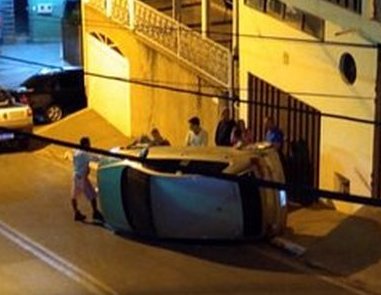 Carro de padre desce rua, bate em passeio e tomba