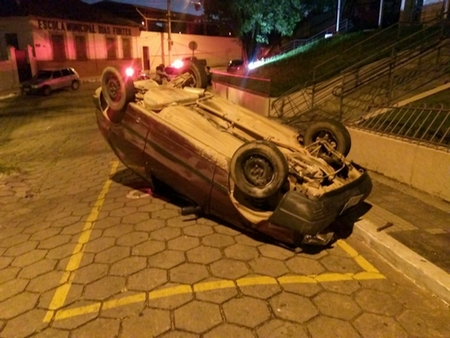 Carro bate em grade de proteção de fórum e capota