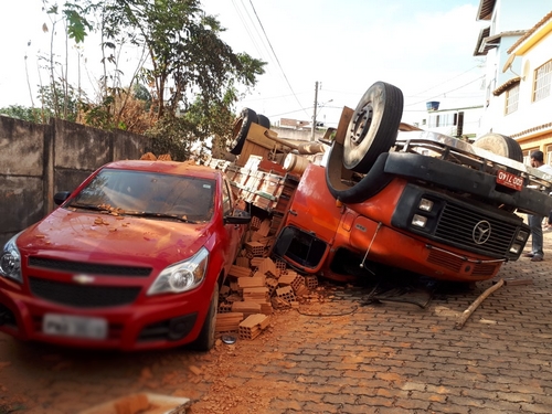 Caminhão desce rua íngreme, capota e atinge caminhonete