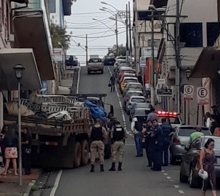 Caminhão desce rua íngreme e bate em parede de loja