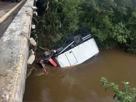 Caminhão cai em rio e bombeiros salvam motorista