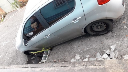 Carro fica com roda presa em bueiro sem grade